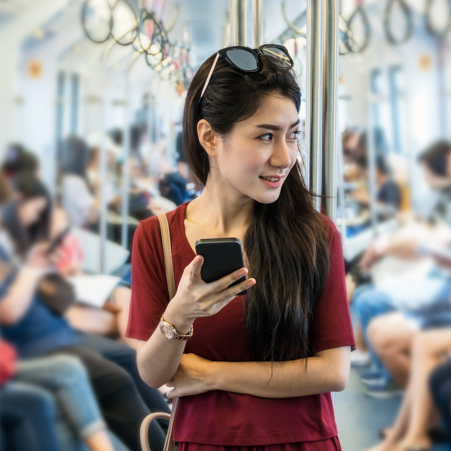 Asian woman passenger with casual suit using the social network via smart mobile phone in the BTS Skytrain rails or MRT subway for travel in the big city, lifestyle and transportation concept